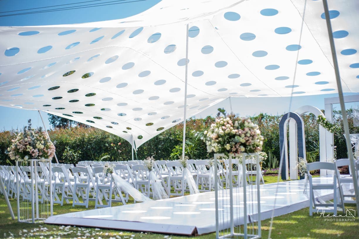 A white aisle and chairs under a stretch tent
